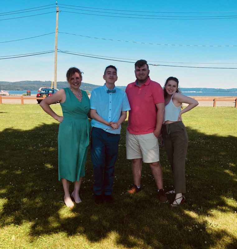 Keri Linardi, RVNAhealth CCO, with her children, from left, Antonio, Trevor and Tiffany, standing under a tree in front of a beach. 